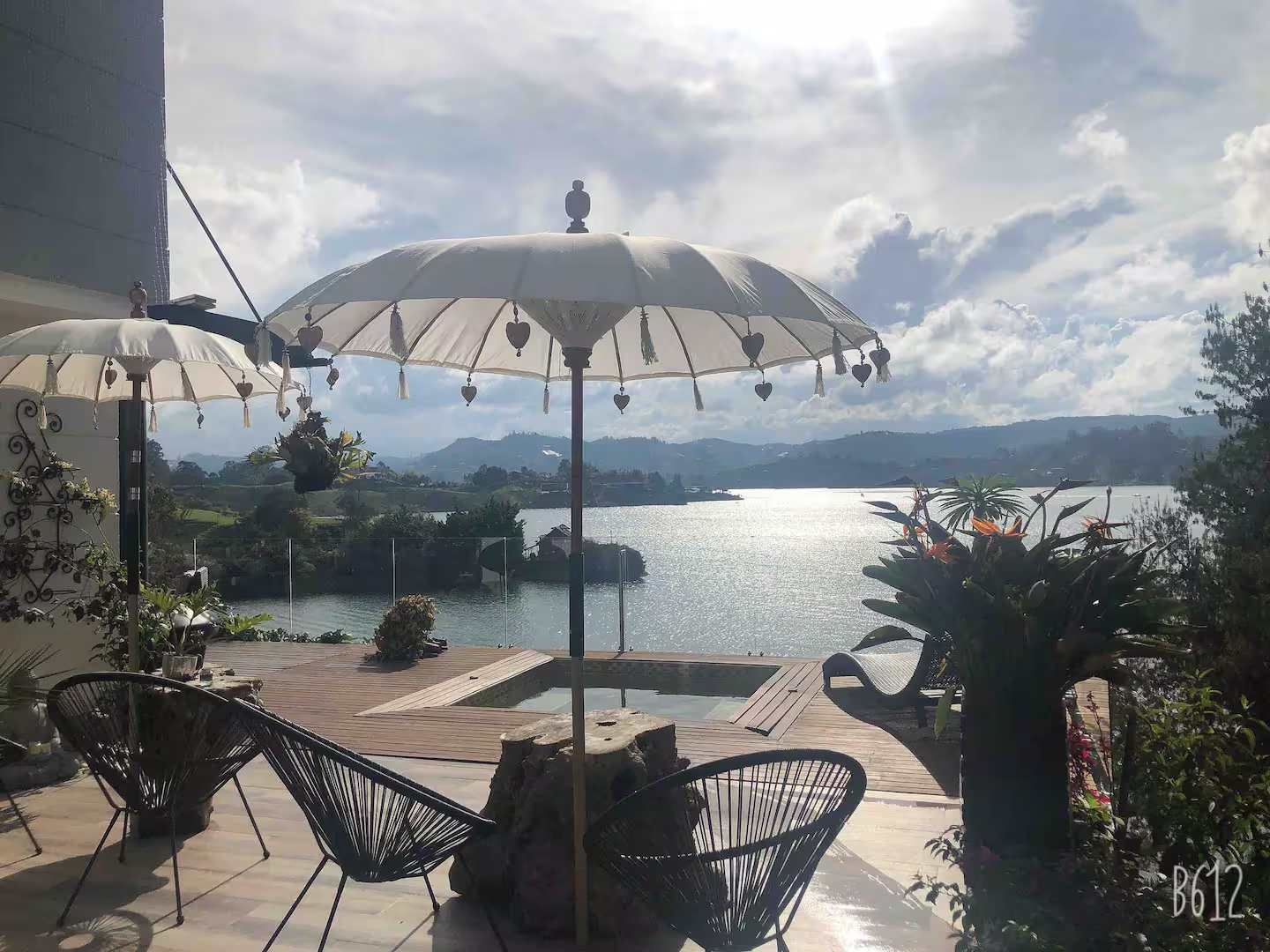 Terraza privada con sombrillas balinesas y vista panorámica al lago Guatapé desde villa de lujo en El Peñol